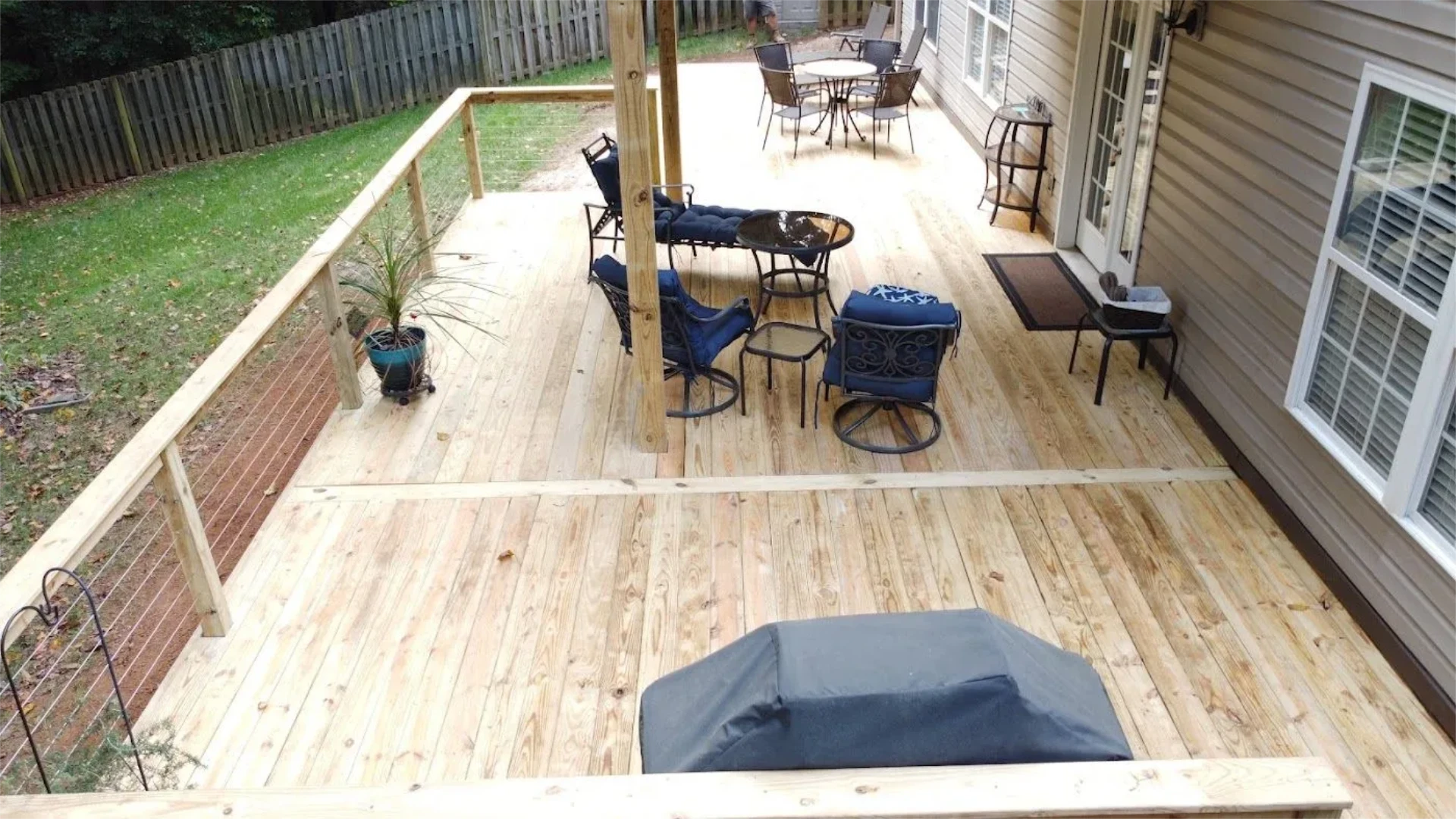 Finished wood deck with cable railing and patio furniture.