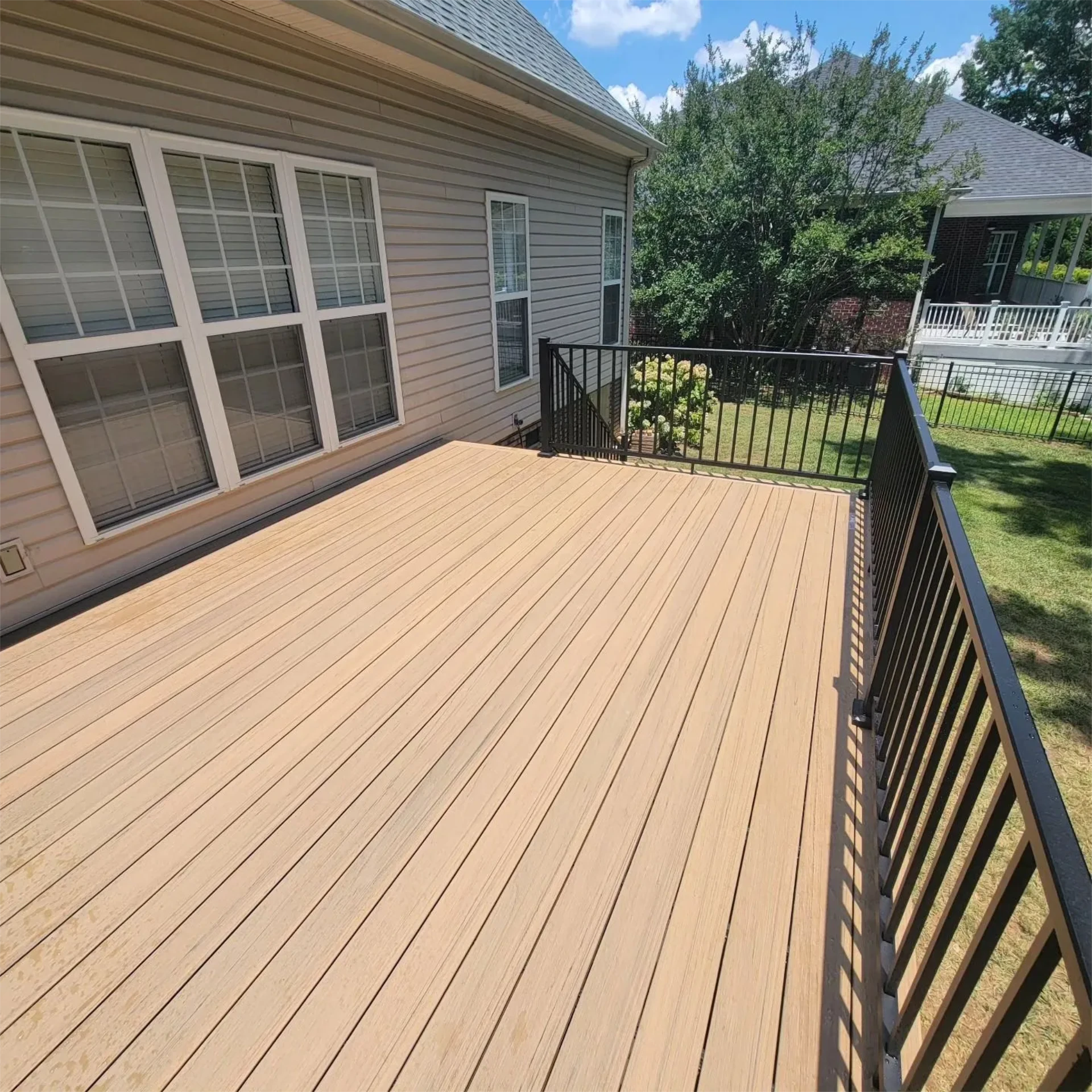 Large tan composite deck beside house windows.