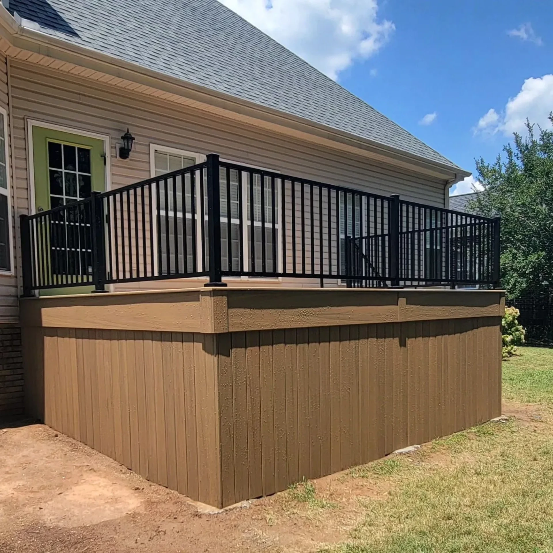 Raised deck with black metal railing and skirting on the grass