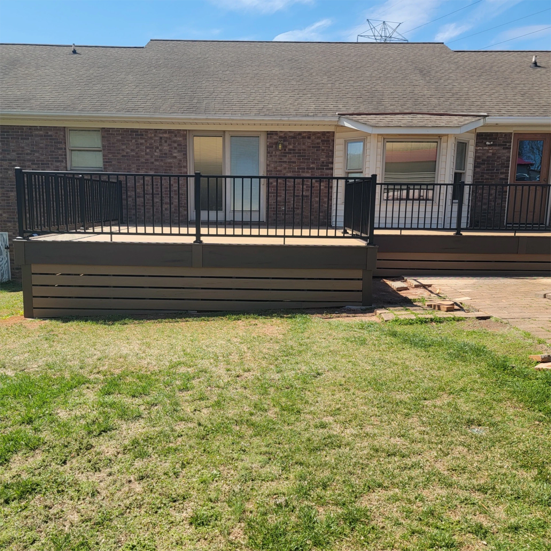 Backyard view of raised composite large wooden deck on a grass below