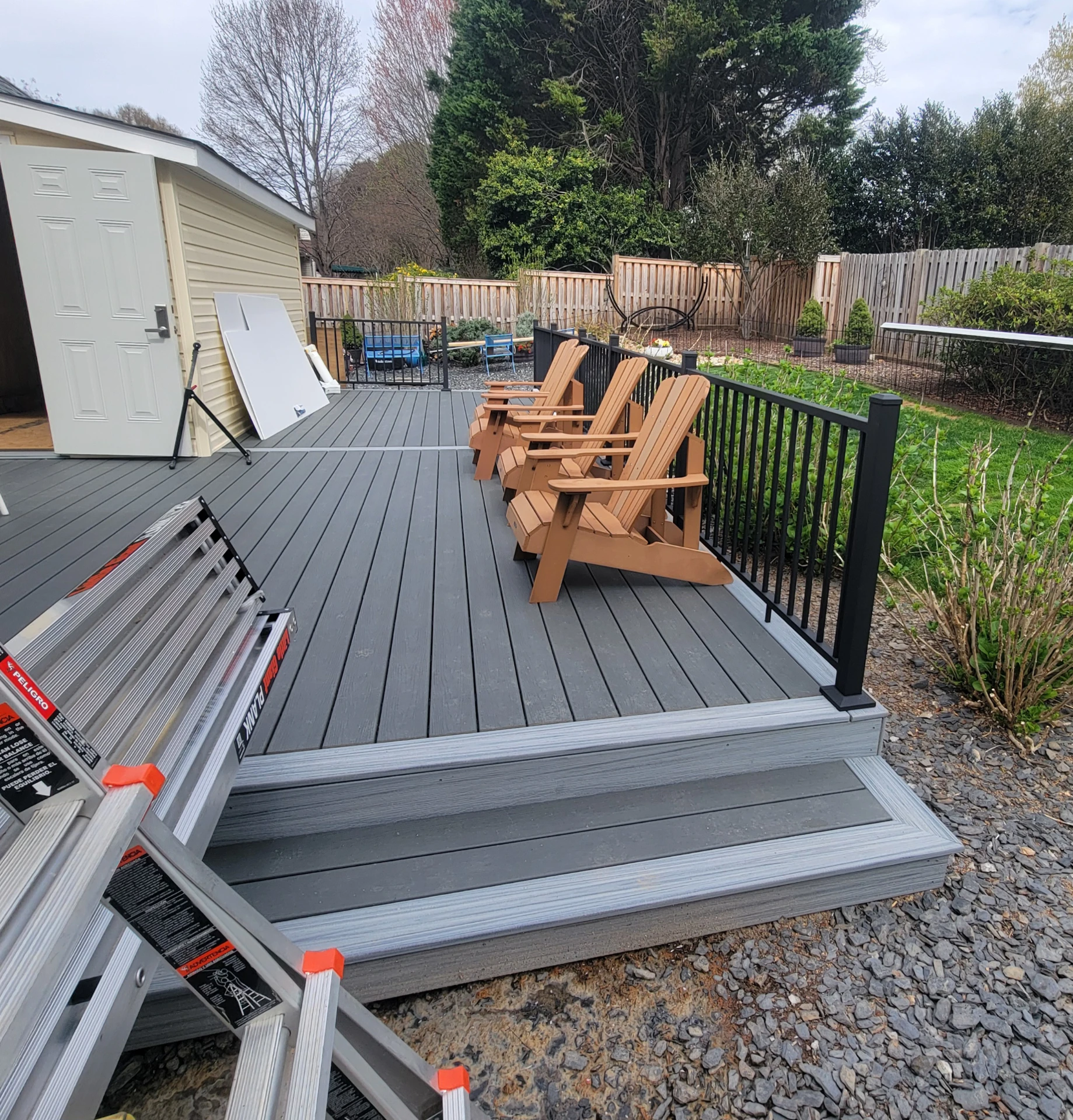 Composite gray deck steps and black metal railing and wooden chair