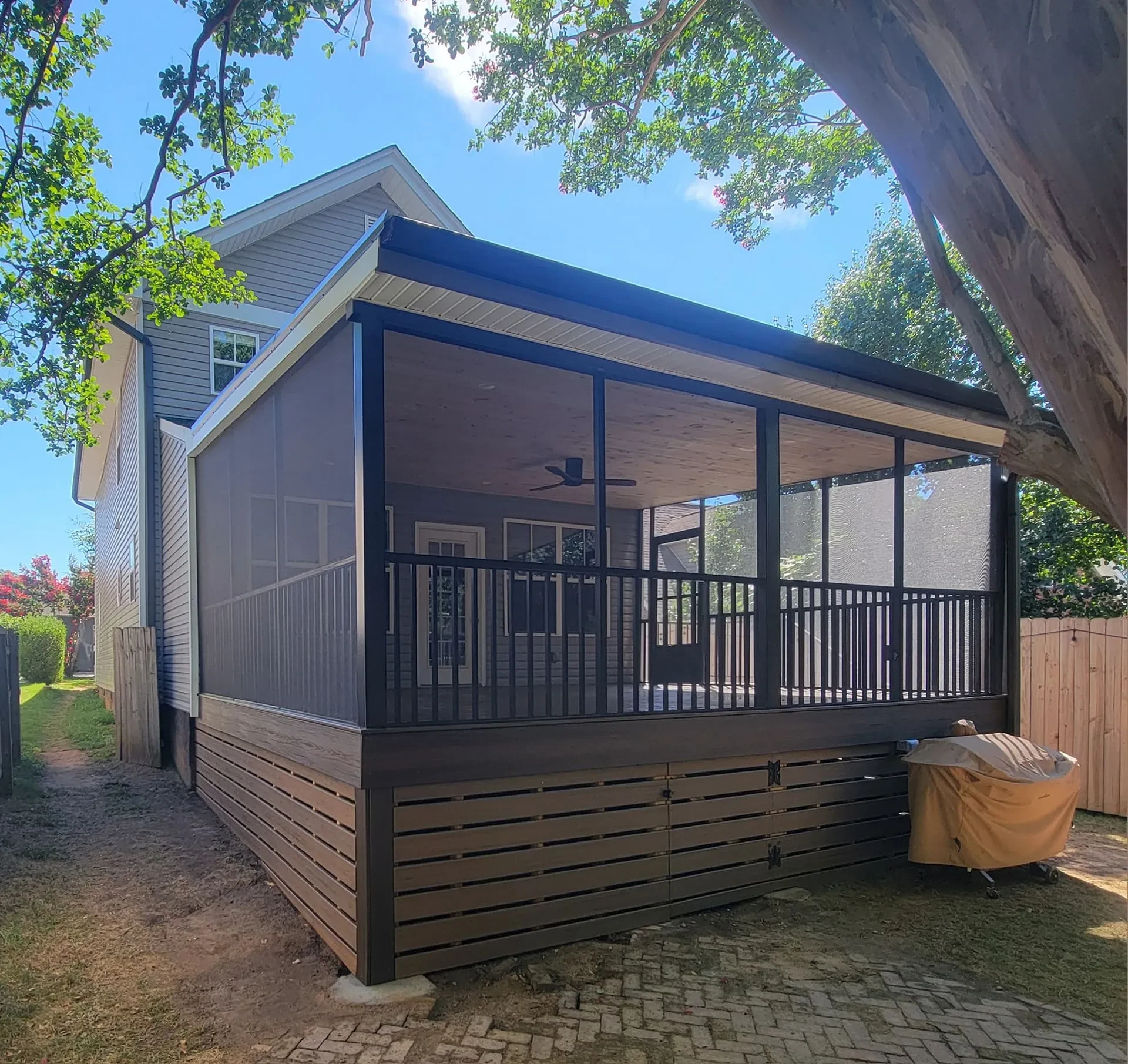 Corner dark view of screened deck enclosure with black railing and small skirting