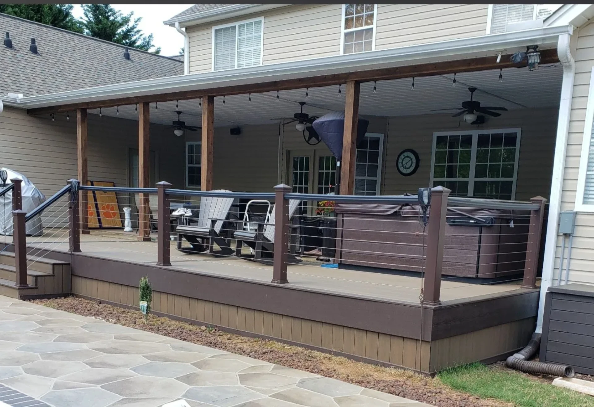 Covered backyard wide deck with cable railing and patio seating