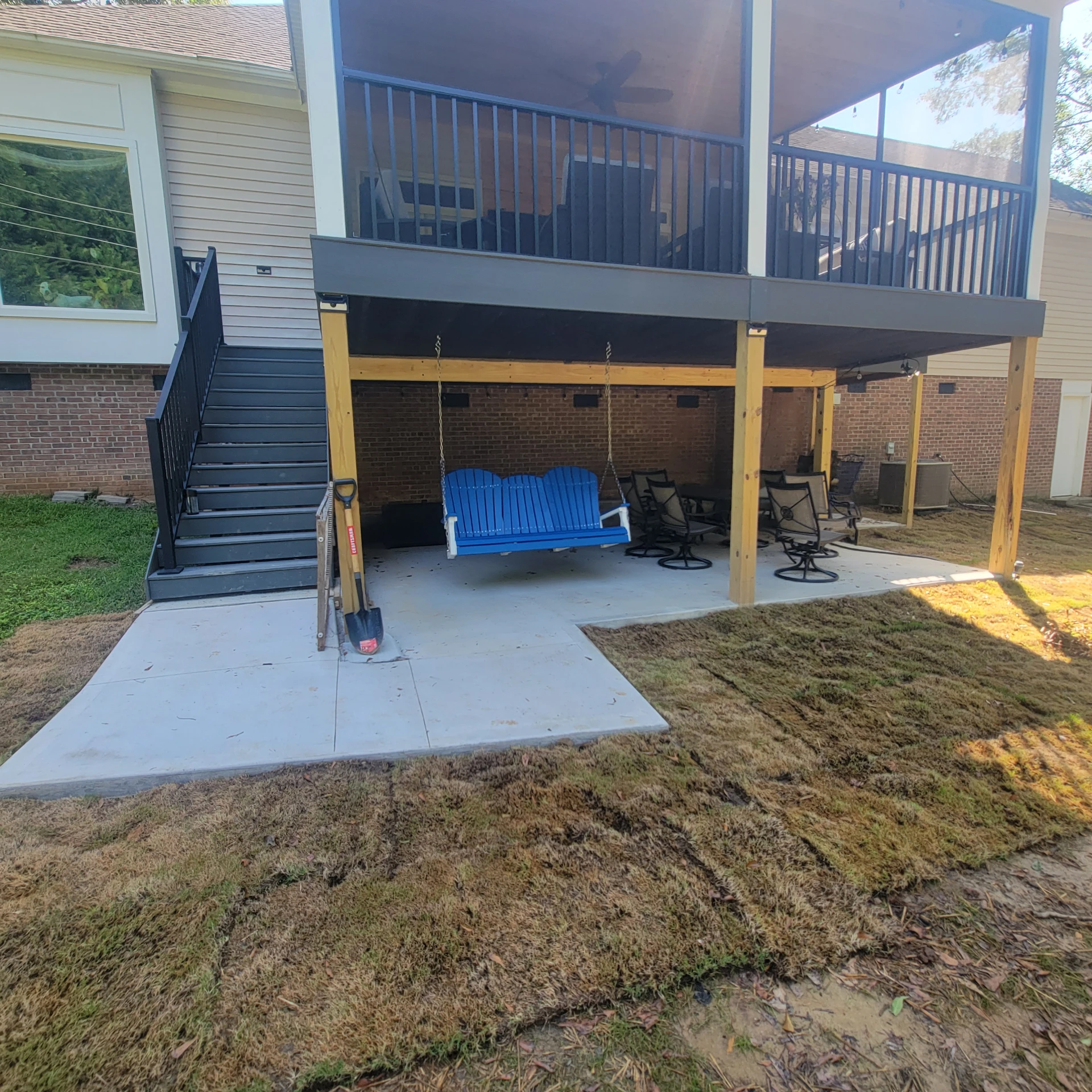Covered elevated black deck and stair with patio seating underneath