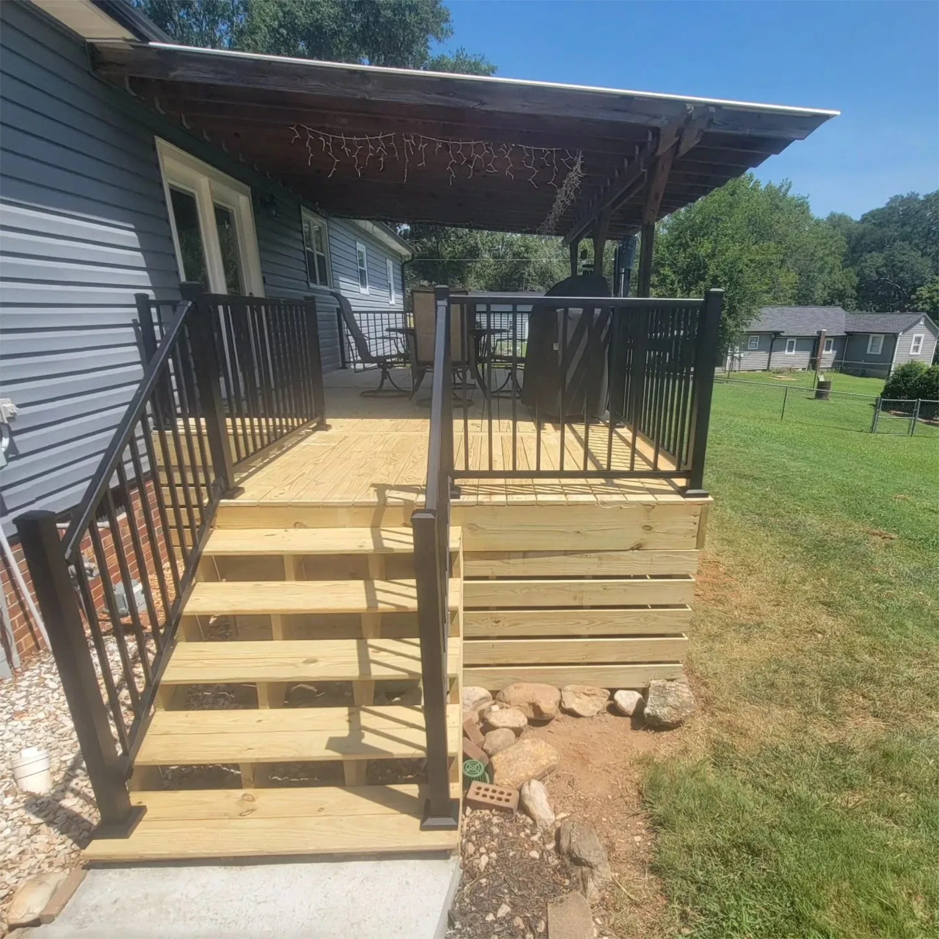 Elevated deck with new covered deck with black railing and stairs