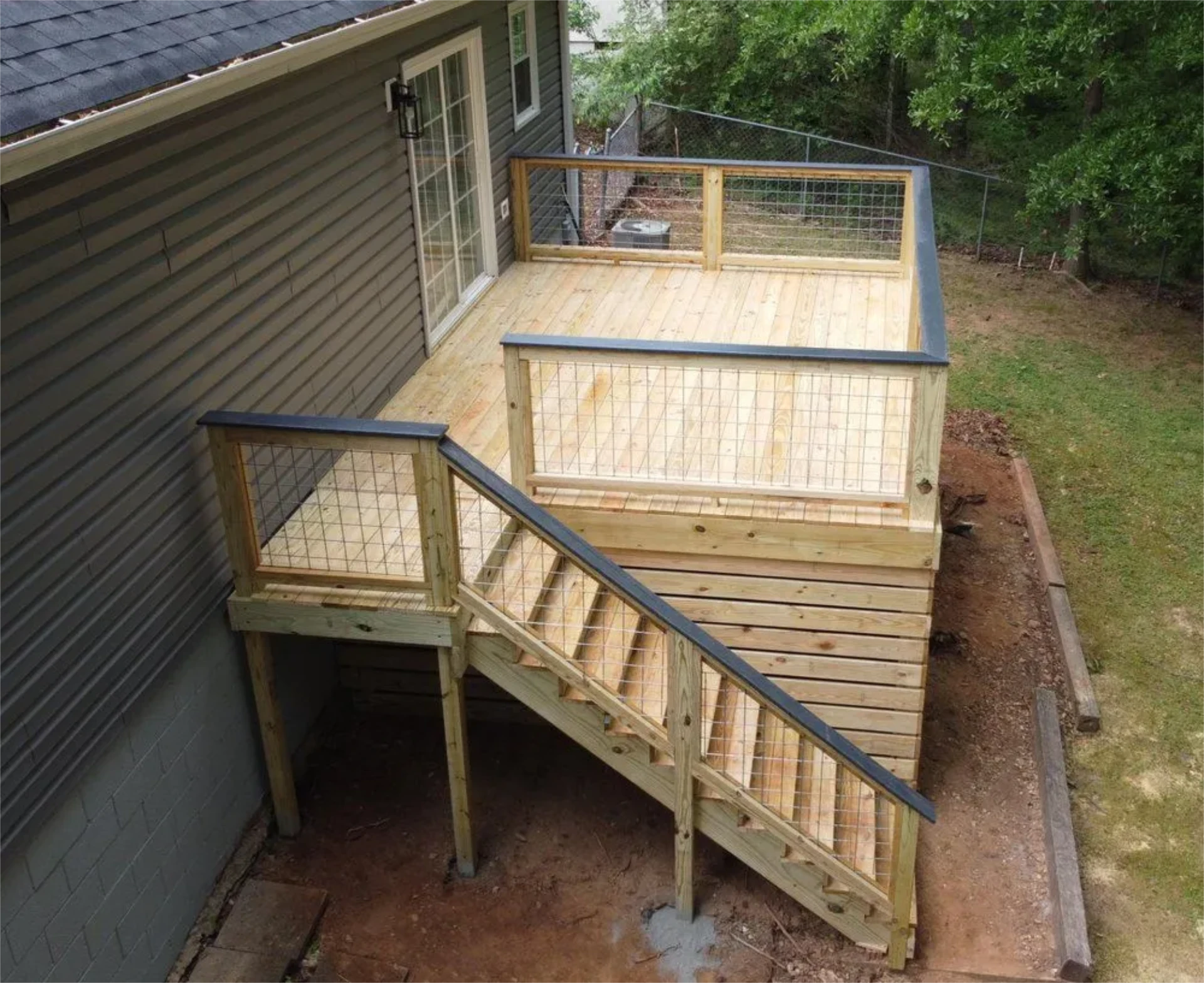 Elevated wooden backyard deck with cable railing and staircase