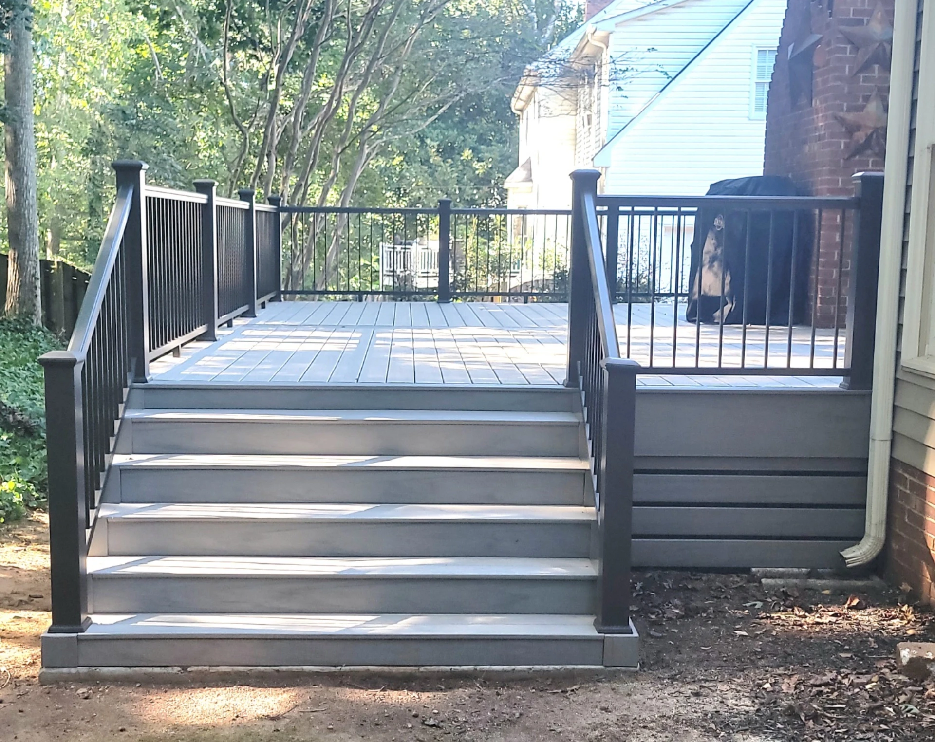 Gray composite deck with stairs and black aluminum railings with beautiful view