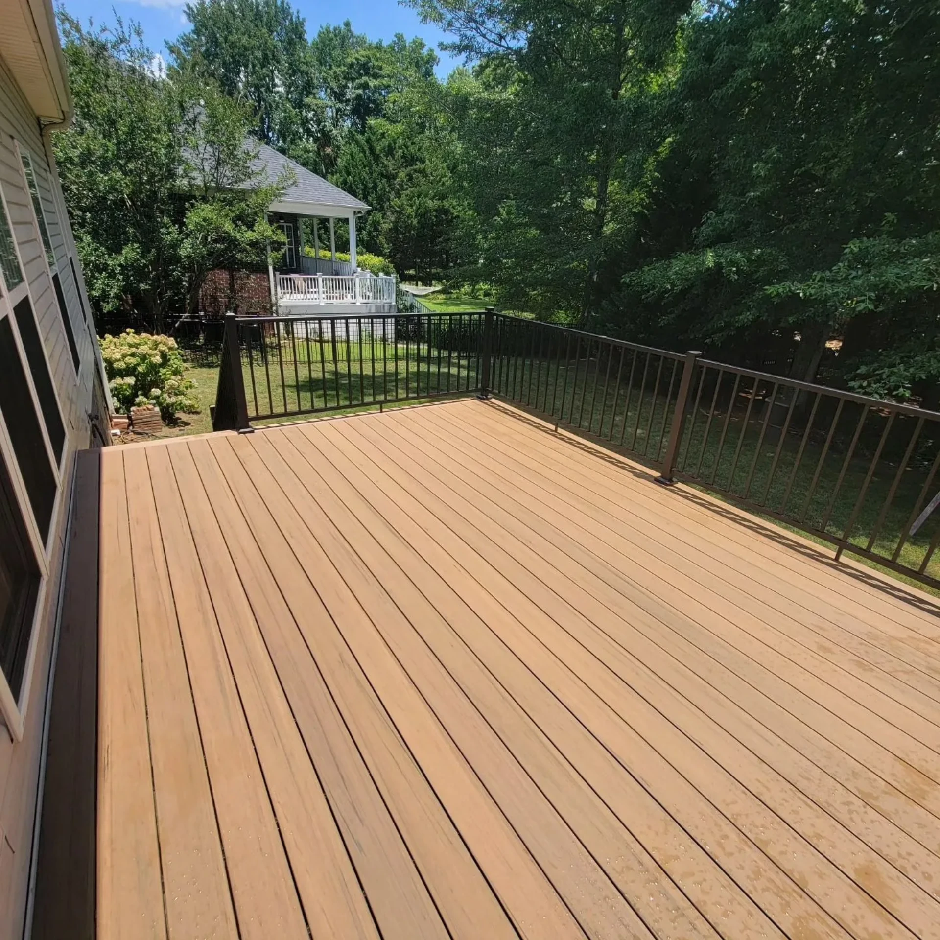 Large composite backyard deck with black railing and overlooking view