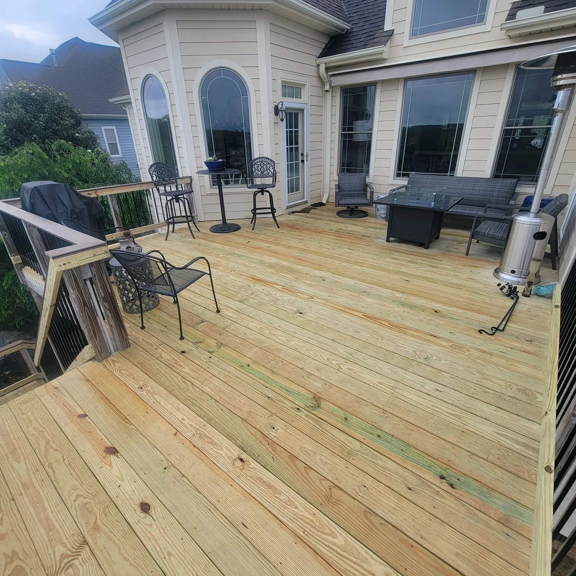 Large wooden deck with patio seating and grill with black railing