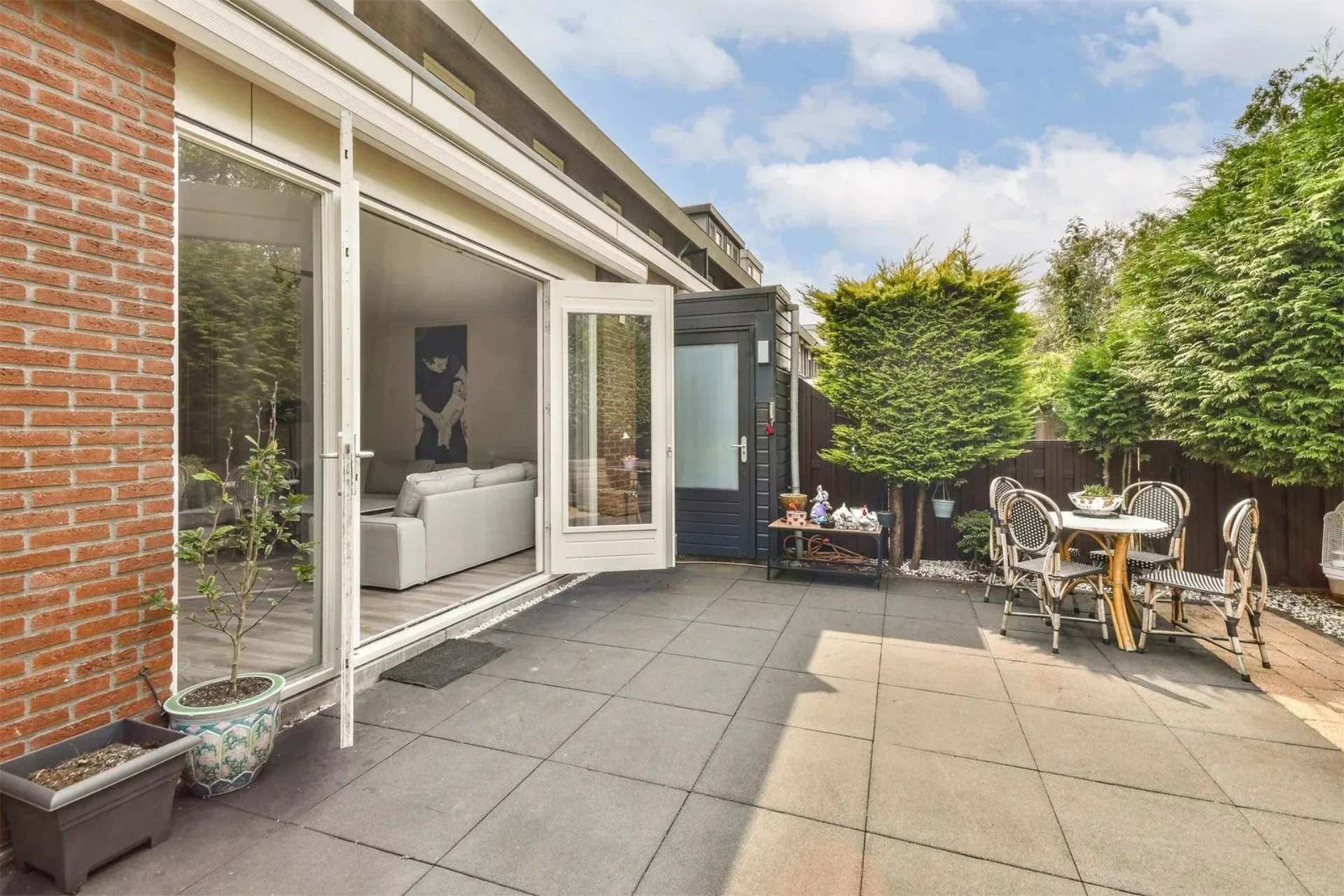 Minimal backyard patio with white open sliding doors and outdoor dining set with great view