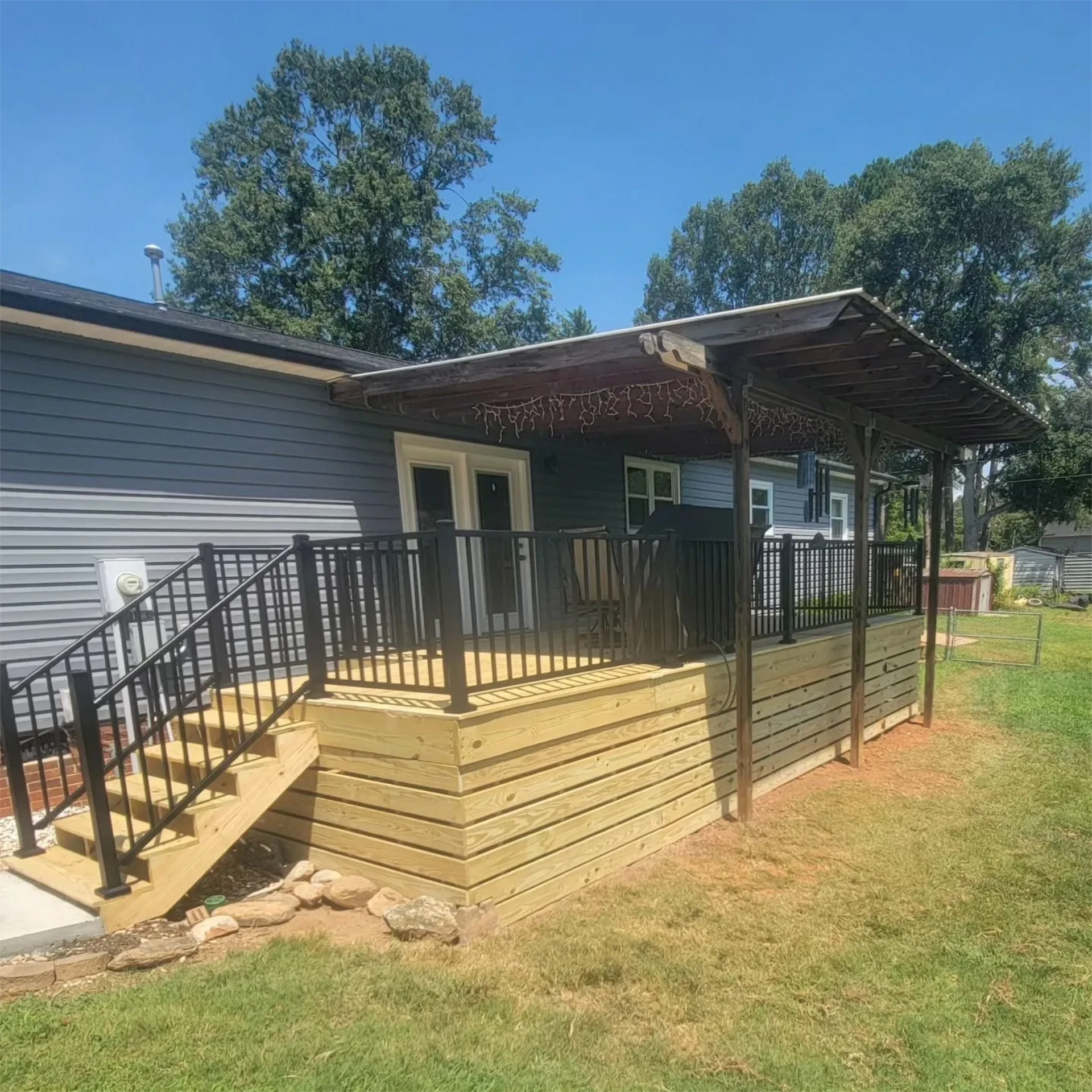 Raised backyard wooden deck with pergola black and black railings
