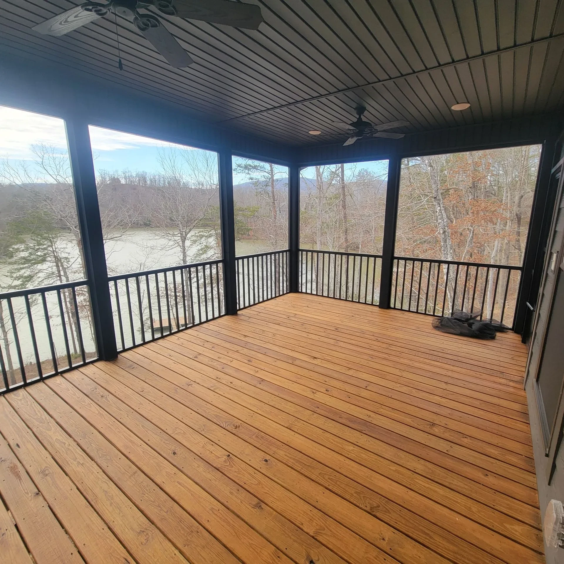 Screened porch and wooden deck with overlooking lake and trees